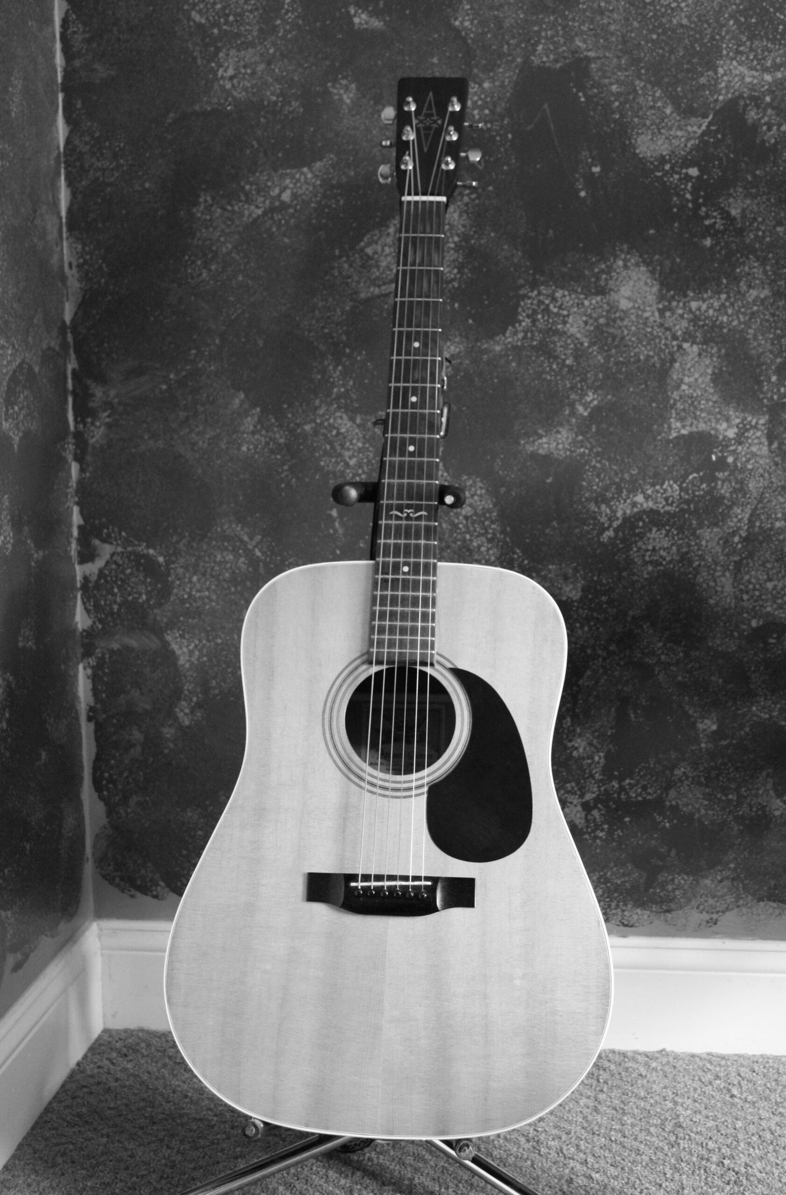Small dreadnought-style acoustic guitar on a stand