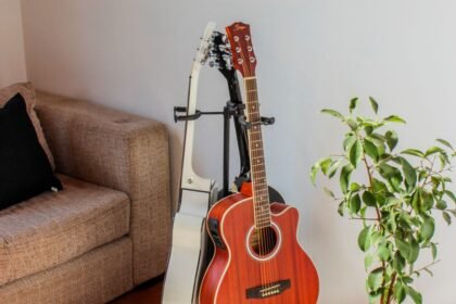 Two acoustic-electric travel guitars on wall-mounted stands in a real living room