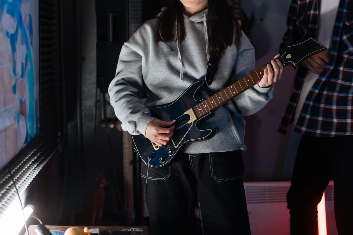 Close-up of hands playing an electric guitar body and pickups