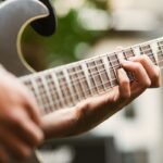 Close-up of a hand fretting notes on an electric guitar neck