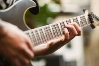 Close-up of a hand fretting notes on an electric guitar neck