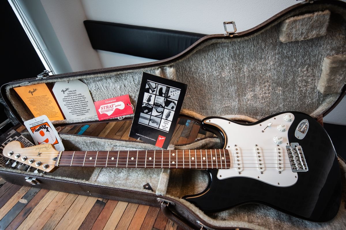 Black moulded hard case for an electric guitar, open showing the lined interior