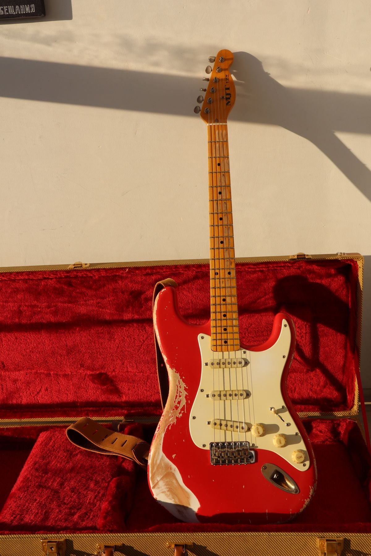 Tweed-covered hard case with an electric guitar resting on top