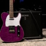 Electric guitar leaning against a Boss combo amplifier backstage