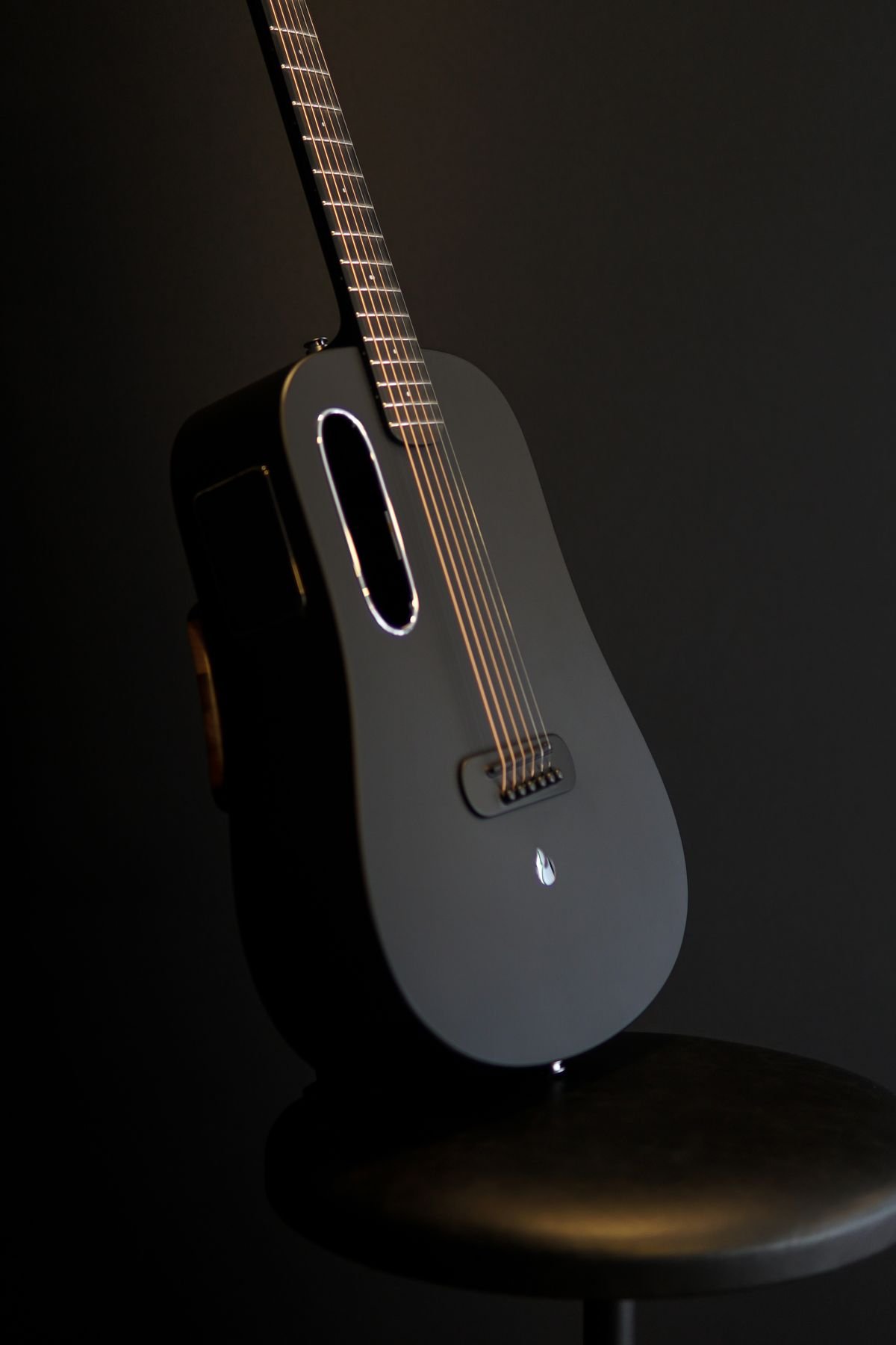 Minimalist one-piece composite acoustic guitar body with an oval soundhole, illustrating unibody carbon fibre construction
