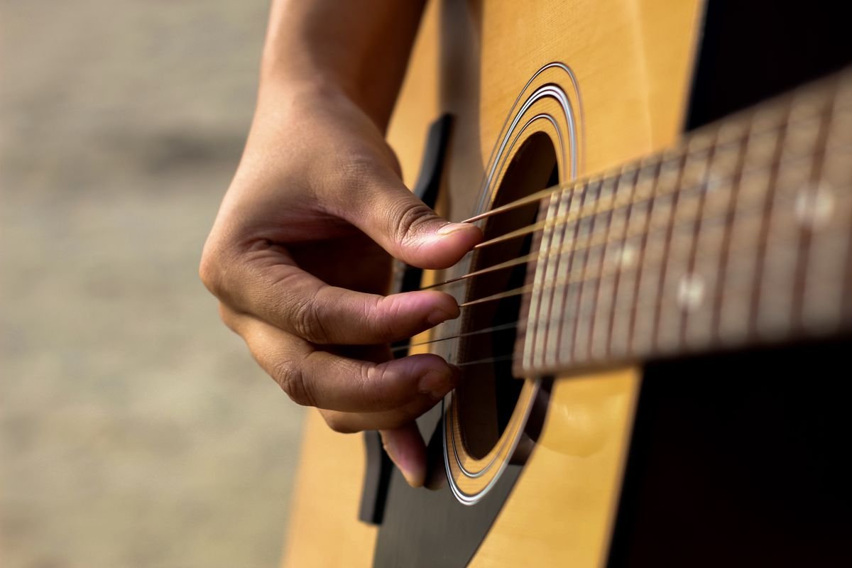Close-up of a hand playing an acoustic guitar near the soundhole
