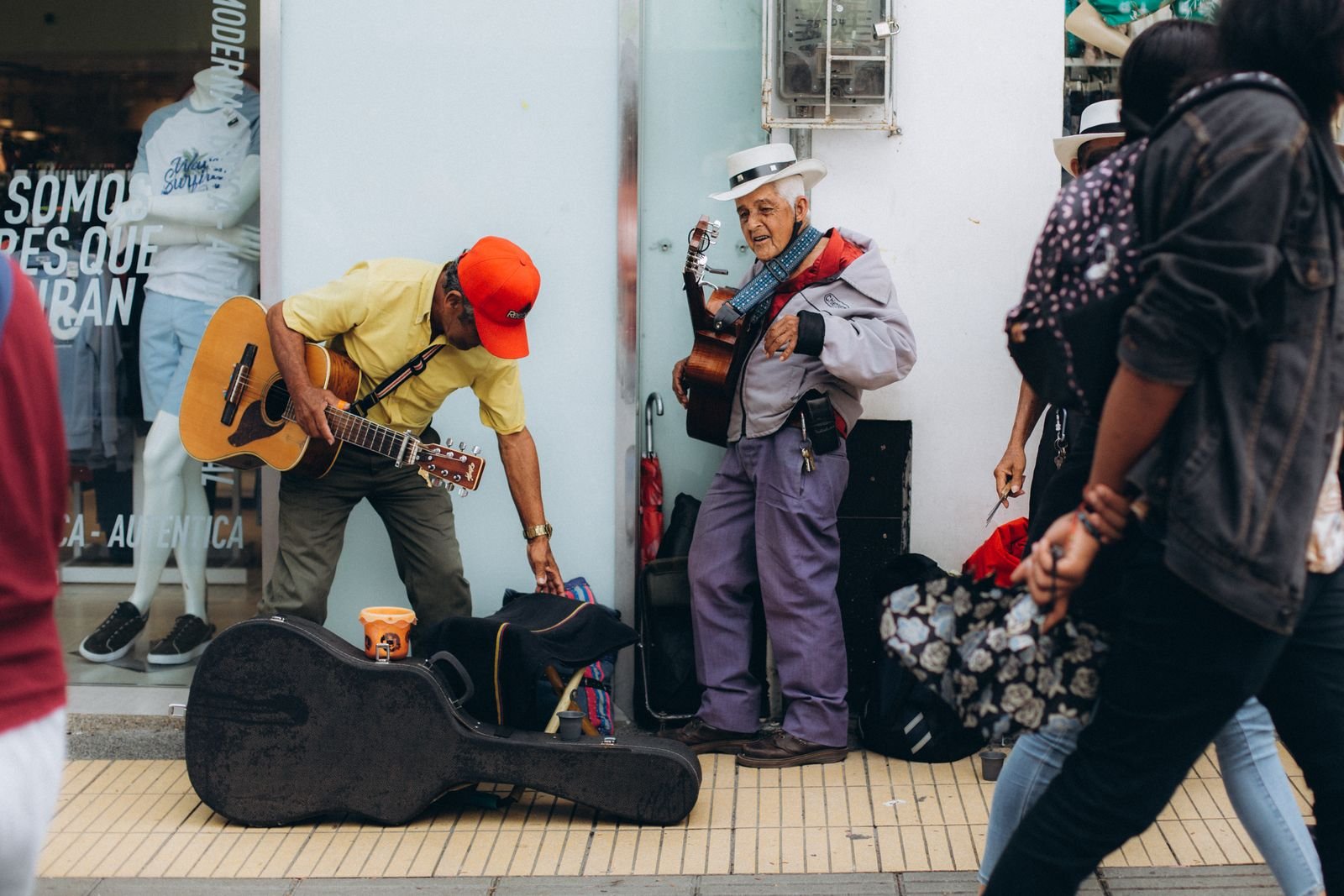Street musicians playing guitar beside an open guitar case
