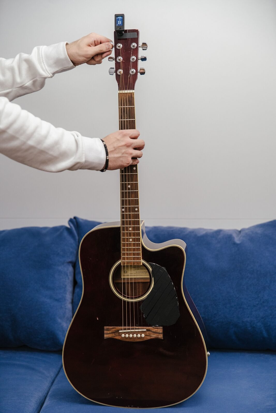 A clip-on tuner attached to a guitar headstock during tuning