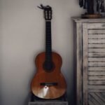 Vintage Viator nylon-string travel guitar leaning against a wall