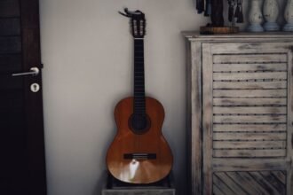 Vintage Viator nylon-string travel guitar leaning against a wall