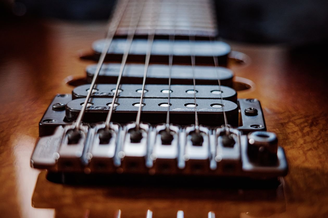 Close-up of an electric guitar bridge and pickups with individually adjustable saddles