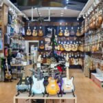 A well-stocked guitar shop wall showing rows of electric and acoustic guitars