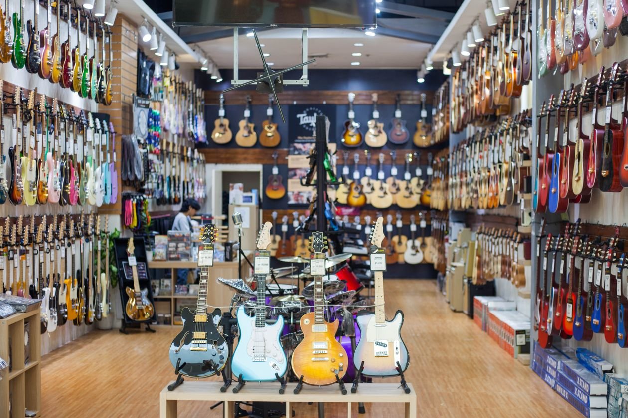 A well-stocked guitar shop wall showing rows of electric and acoustic guitars