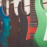 A row of electric guitars in a shop, illustrating the kind of solid-body electric feel a travel electric like the HUSH X Live is trying to match