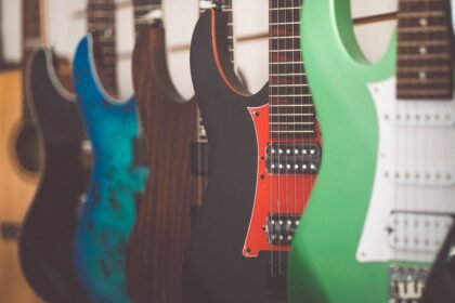 A row of electric guitars in a shop, illustrating the kind of solid-body electric feel a travel electric like the HUSH X Live is trying to match