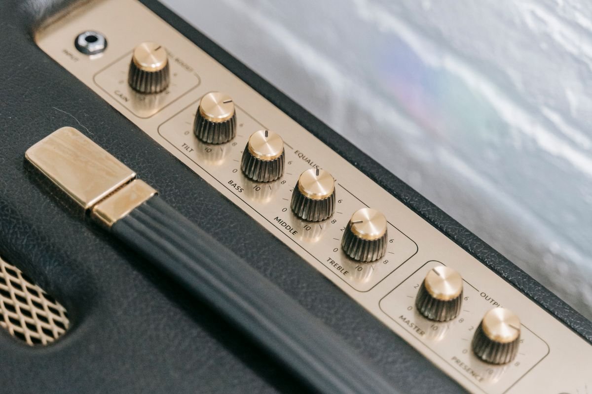 Close-up of a guitar amplifier's cream control panel with gain, bass, middle, treble and master volume knobs, and a carry handle, similar to the Fishman Loudbox Mini Charge
