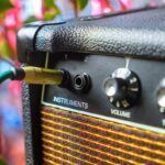 Close-up of an acoustic amplifier's instrument input jack with a cable plugged in, next to volume and treble controls, similar to the Fishman Loudbox Mini Charge's front panel