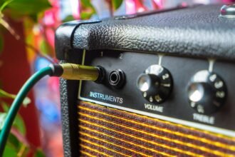 Close-up of an acoustic amplifier's instrument input jack with a cable plugged in, next to volume and treble controls, similar to the Fishman Loudbox Mini Charge's front panel