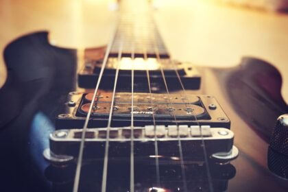 Close-up of a single humbucker pickup and fixed bridge on a solid-body electric guitar