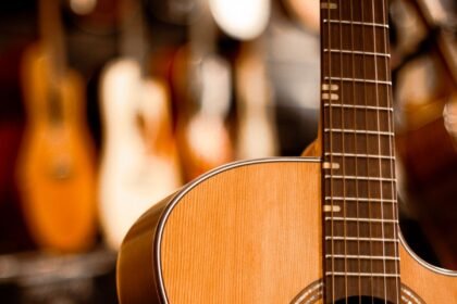 A cutaway acoustic guitar hanging in a guitar shop with other guitars blurred behind it