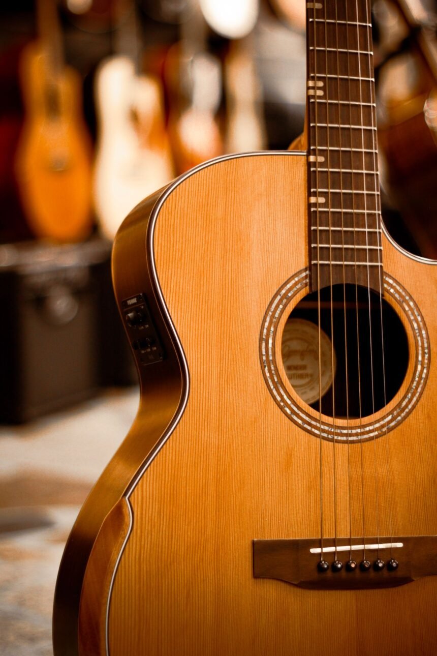 A cutaway acoustic guitar hanging in a guitar shop with other guitars blurred behind it