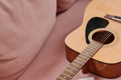 A mahogany acoustic-electric travel guitar body and neck resting on a sofa