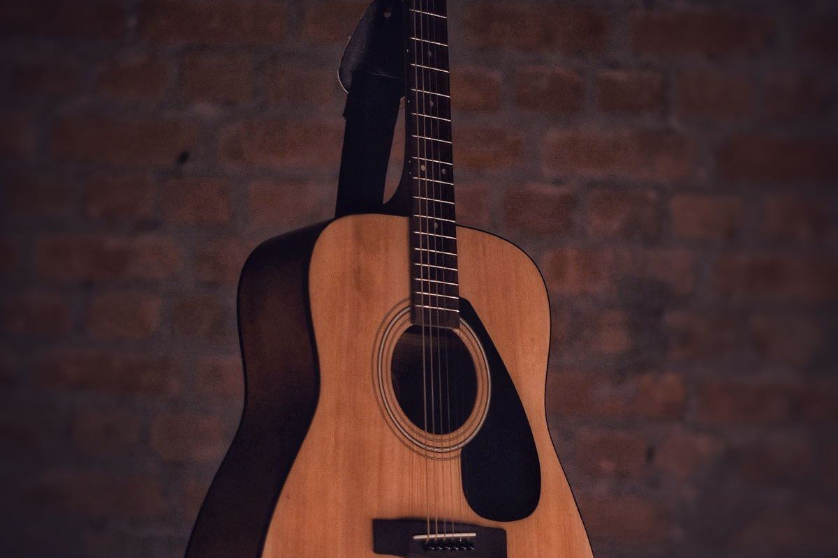 Close-up of an acoustic guitar soundhole, bridge and neck against a brick wall