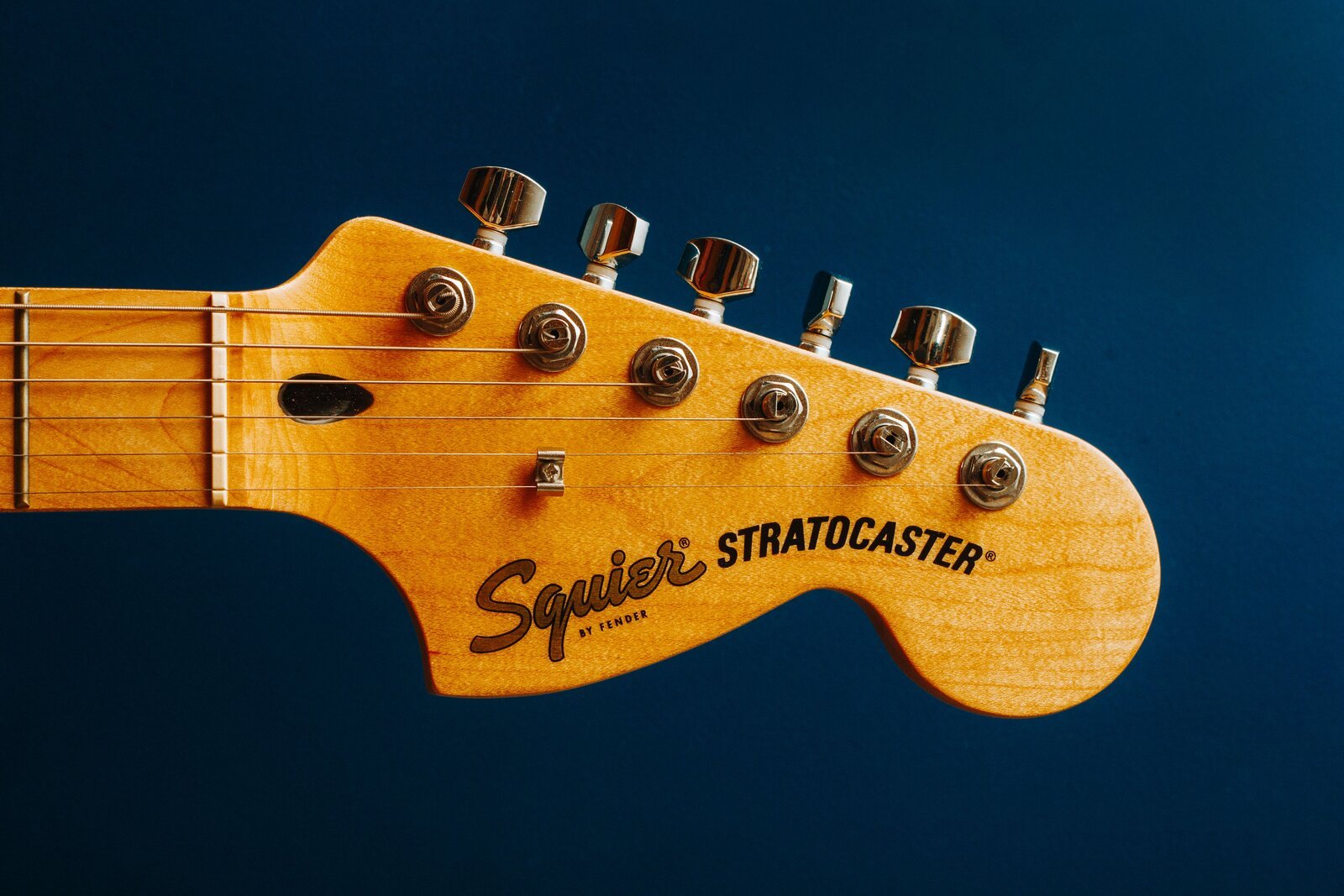 Squier by Fender Stratocaster headstock close-up showing the sealed die-cast tuning machines