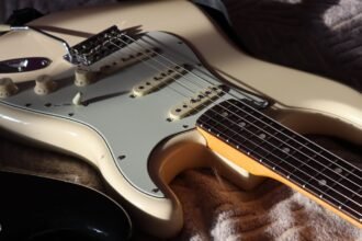 Close-up of a Stratocaster-shaped guitar body showing single-coil pickups and control knobs