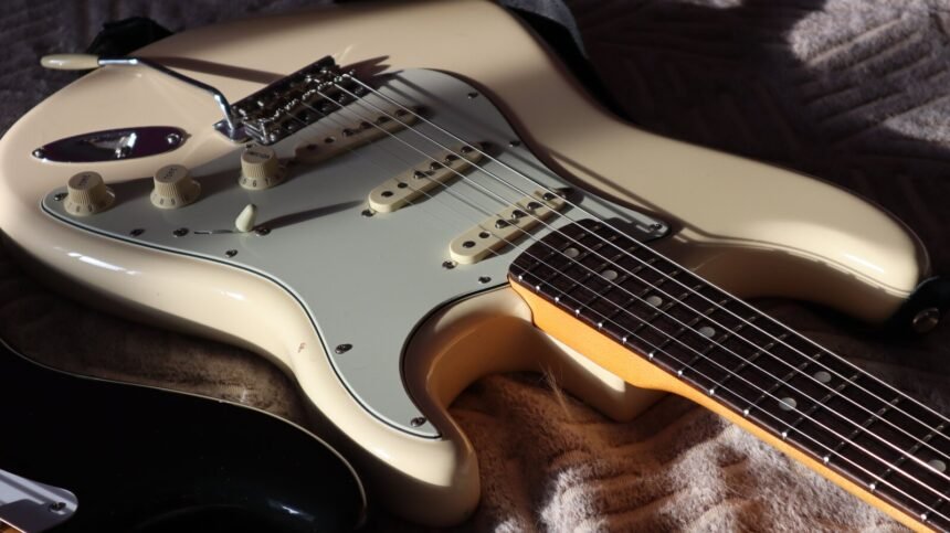 Close-up of a Stratocaster-shaped guitar body showing single-coil pickups and control knobs