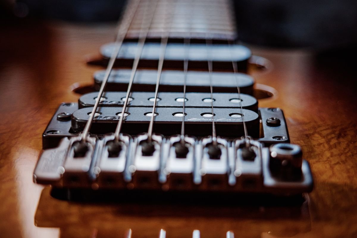 Close-up of a solid-body electric guitar's two pickups and strings, illustrating a dual-pickup electronics layout