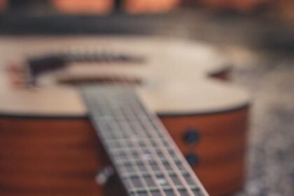 A small acoustic guitar body and neck resting on gravel outdoors