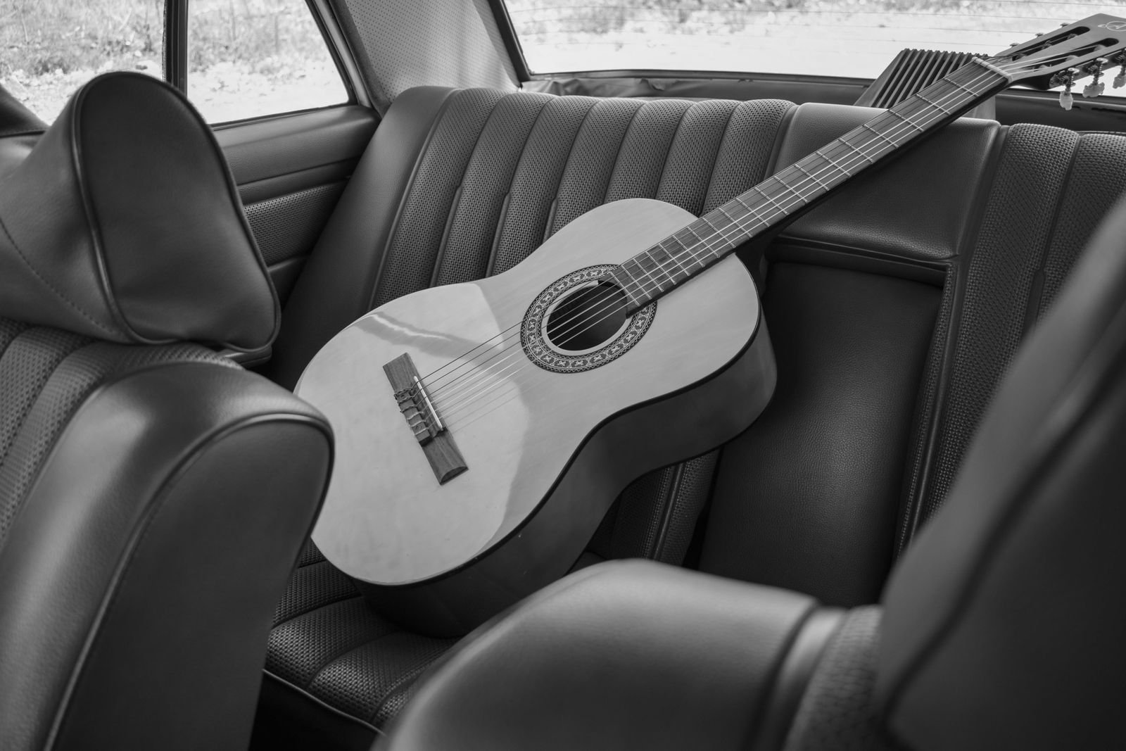 A classical acoustic guitar left on the back seat of a car