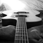 A full-size acoustic guitar resting on a bed, illustrating the size and space a standard guitar takes up at home