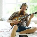 Practising an electric travel-style setup with headphones in a small bedroom