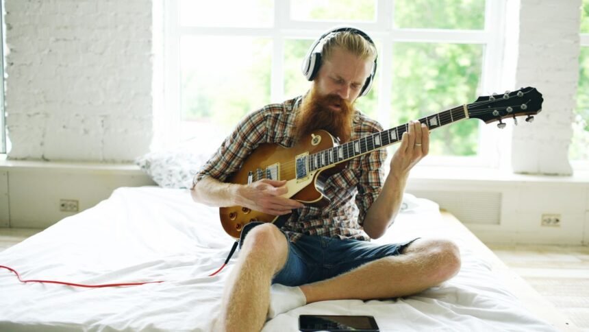 Practising an electric travel-style setup with headphones in a small bedroom