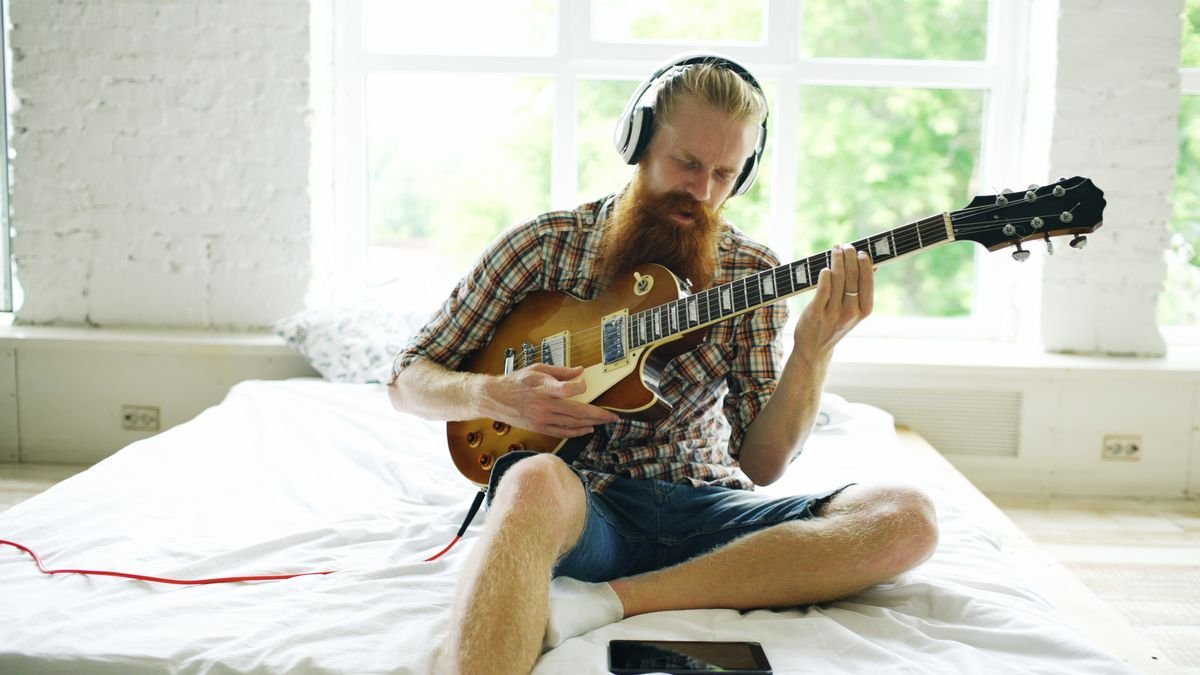 Practising an electric travel-style setup with headphones in a small bedroom