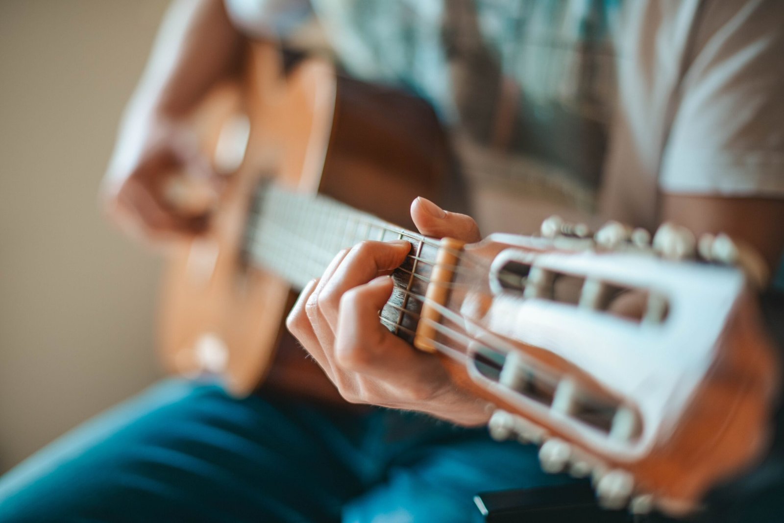 Close-up of a hand fretting an acoustic guitar neck near the headstock