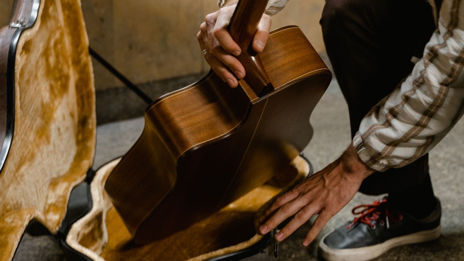 Guitar being placed into an open hard case with a plush lined interior