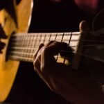 Close-up of a hand fretting a chord low on the neck while learning