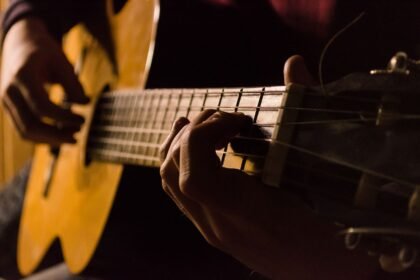 Close-up of a hand fretting a chord low on the neck while learning
