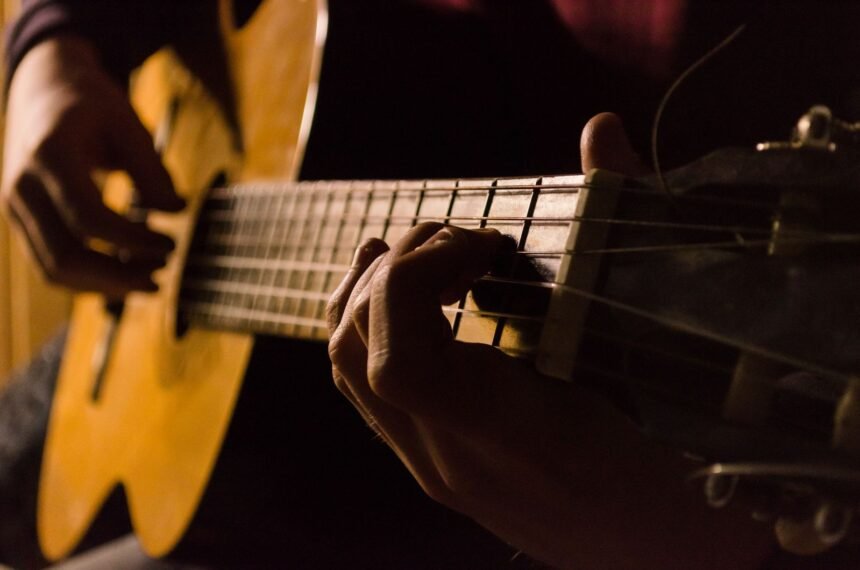 Close-up of a hand fretting a chord low on the neck while learning