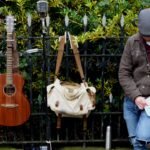 A guitar and travel bag leaning against a railing, the kind of road use a Martin Backpacker is built for