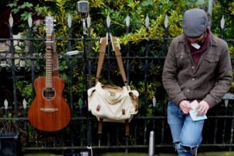 A guitar and travel bag leaning against a railing, the kind of road use a Martin Backpacker is built for