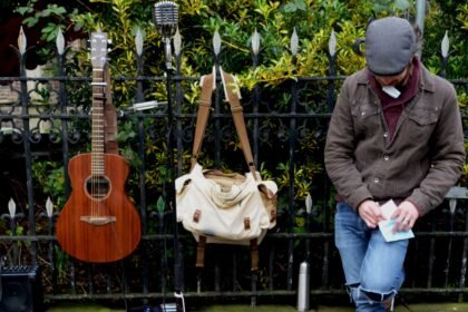 A guitar and travel bag leaning against a railing, the kind of road use a Martin Backpacker is built for
