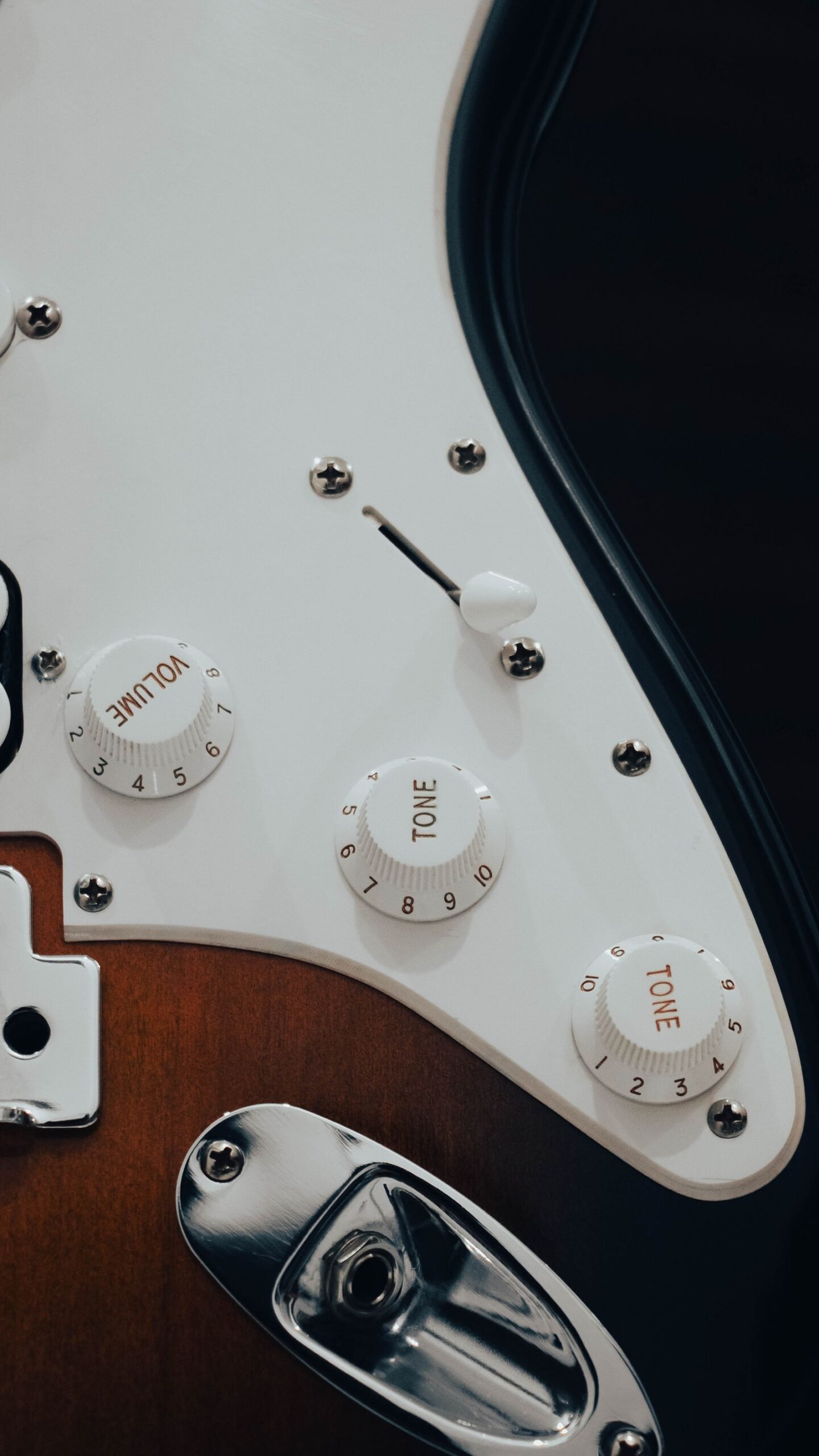 Close-up of an electric guitar's volume and tone knobs and pickup selector switch