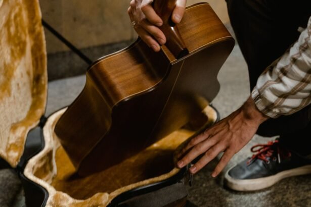 A musician carefully fits an acoustic guitar body into a hardshell case, illustrating the packing problem travel guitars solve