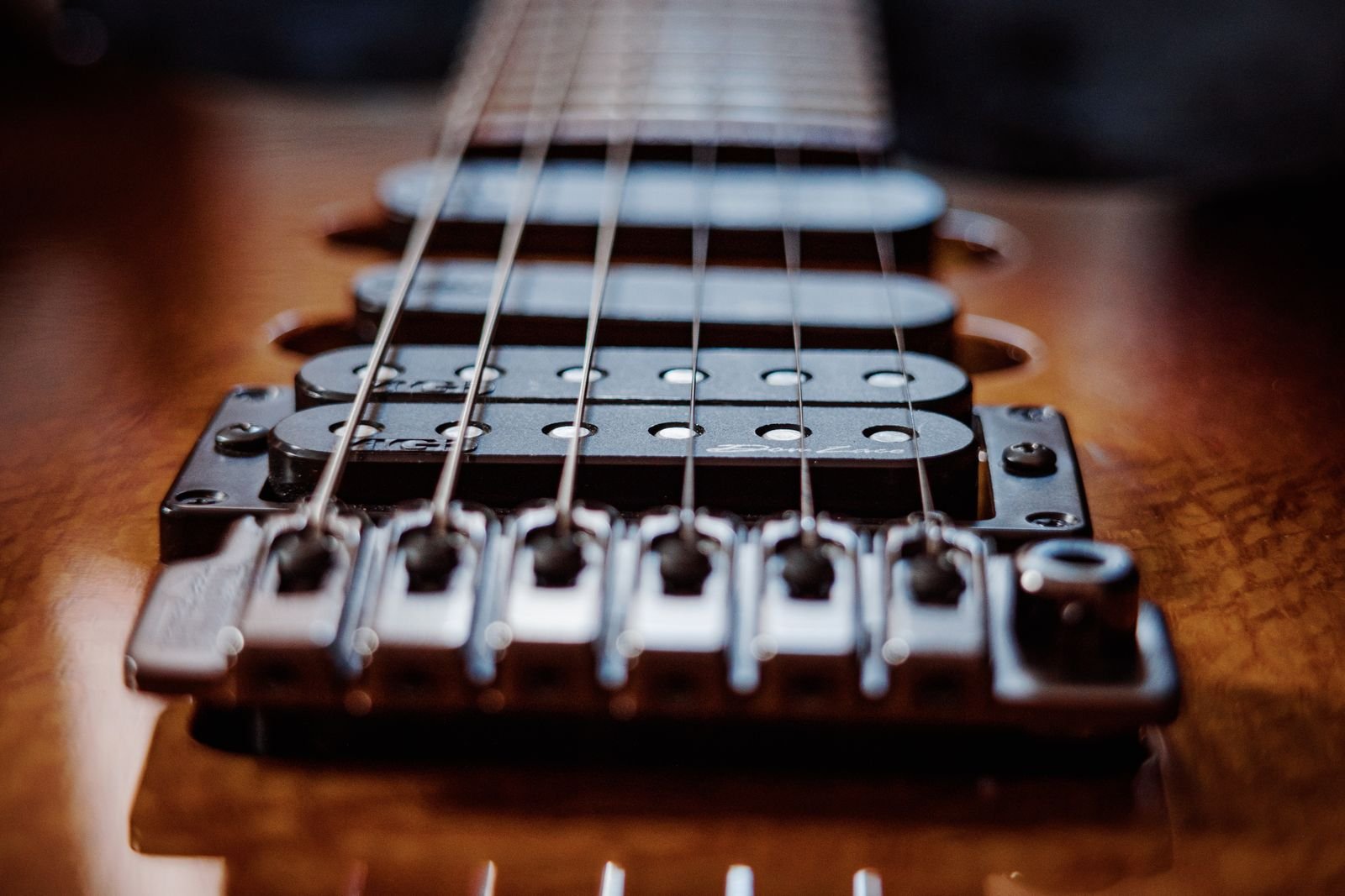 Close-up of an electric guitar's strings and fixed bridge
