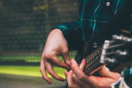 A musician's hands fingerpicking a bass guitar, illustrating the compact ultra-light travel bass format
